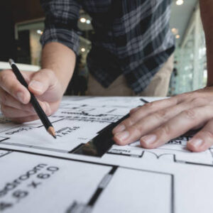 A male architect measuring and marking the scale ratio of sizes of a complicated blueprint.